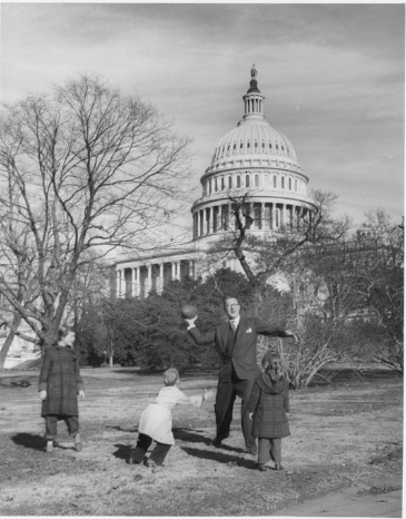 Kefauver playing football with his children in front of the US Capitol.